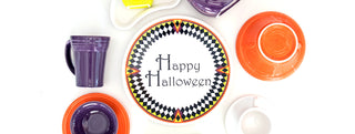 Harlequin plate with Happy Halloween written on the plate, surrounded by orange, white, purple various Fiesta dinnerware