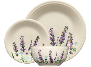 Ivory-colored dinner plate, salad plate, and bowl featuring lavender and small blue flower designs, displayed against a white background.