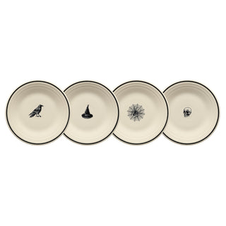 Four cream-colored plates with black rims, each featuring a different Halloween-themed design: a raven, a witch hat, a spider web, and a skull, arranged in a row.