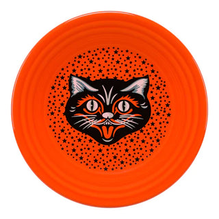 An orange plate featuring a vintage-style black cat face with wide eyes and an open mouth, surrounded by a pattern of small black stars.