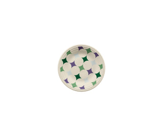 A round white plate with a geometric pattern of overlapping green, purple, and blue shapes forming a circular design.