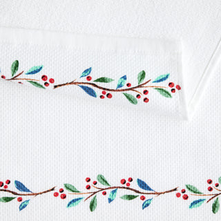 Add festive charm to your kitchen with the Nutcracker Ballerina Holiday Holly Sprig Kitchen Towel Set by Town and Country, featuring white cotton towels with hand-painted holly branches, red berries, and green and blue leaves—perfect for holiday decor.