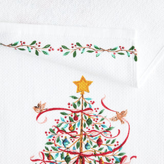 The Town and Country Holly Berry Christmas Tree Kitchen Towel Set features a festive tree with ornaments, red ribbons, a yellow star, two birds, and a leafy green-red border—perfect for adding holiday charm to your kitchen.