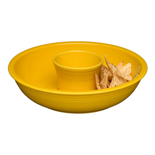 The Fiesta New Retired 2-Piece Chip and Dip Set, 12 7/8" in Daffodil, made in the USA from lead-safe china, holds chips around a central dip cup. The empty dish, except for several tortilla chips, is set against a white background.