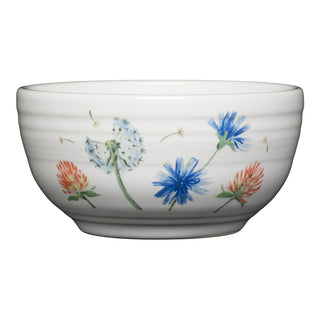 The Fiesta Breezy Floral Bistro Coupe 5 1/2 Inch Cereal Bowl, 22 oz, features hand-painted blue, red, and white wildflowers with dandelions. This white ceramic bowl is microwave safe for your convenience.