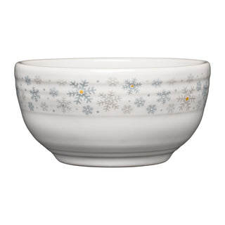 The Fiesta White Snowflakes Bistro Coupe 5 1/2 Inch Cereal Bowl (22 oz) features a smooth white ceramic surface with delicately curved sides and a subtle rim. Blue, gray, and yellow snowflakes encircle the upper edge, making it an ideal festive holiday cereal bowl or a charming seasonal addition to your winter table.