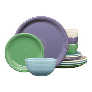 The Fiesta Factory Direct Lavender Bloom Mixed Color Bistro Coupe 12-Piece Dinnerware Set features plates and bowls in purple, green, blue, and cream, stacked neatly against a white background.