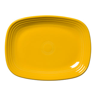 A Fiesta New Retired 12 Inch Large Rectangular Platter in Daffodil, made in the USA, features rounded edges and embossed concentric lines near the rim. Set against a white background.