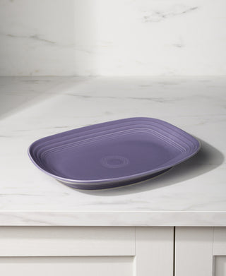The Fiesta Lavender 12 Inch Large Rectangular Platter, featuring a ridged design, sits on a white marble countertop in a bright kitchen.