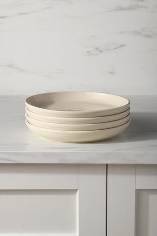 A set of four Fiesta Linen Coupe 10 3/8 Inch Dinner Bowls (40 oz each) is stacked on a white marble countertop, backed by a light gray and white marble backsplash.