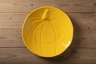 A yellow Fiesta Pumpkin Shaped Plate, 8 1/2 inches in size and textured like a real pumpkin, rests on a wooden surface, its festive harvest hues perfectly capturing the seasonal spirit and beautifully complementing classic Fiesta dinnerware.