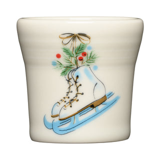 The Fiesta Jolly Christmas Skates 1 1/2 OZ Ceramic Shot Glass features cream ceramic with white vintage skates, brown laces, pine branches, red berries, and a gold bow—ideal festive holiday drinkware for your display.