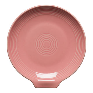 The Fiesta New Retired Extra Large Spoon Rest 7 Inch is a round, pink ceramic utensil holder with concentric raised rings and a small handle, perfect for stylish, heat-resistant kitchen use.