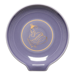 The Fiesta Lavender Dancing Lady Extra Large Spoon Rest (7 inch) features a gold-outlined woman in a flowing dress and hat within a circular border. Made in the USA, it’s heat-resistant with ridged edges and a small pouring spout.