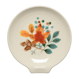 The Fiesta Autumn Fields Extra Large Spoon Rest 7 Inch is a round, cream-colored dish decorated with a fall-themed design featuring orange and yellow leaves, blue-green leaves, brown acorns, and blue dots centered on the plate—a charming addition to autumn table settings or the perfect oversized spoon rest.