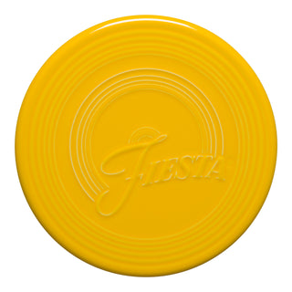 The Fiesta New Retired Extra Large Trivet, 8 1/4 inch, is a round, bright yellow ceramic trivet with concentric ridges and "Fiesta" embossed in script—perfect as a heat-resistant addition to your kitchen.