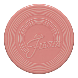 The Fiesta New Retired Extra Large 8 1/4 Inch Trivet features a round, pink ceramic design with concentric circles and embossed "Fiesta" script—stylish and heat-resistant for your table.