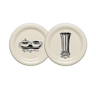 A set of two cream-colored Fiesta plates: one featuring a black illustration of a sugar bowl and creamer, inspired by classic Fiesta Icons, and the other showcasing a medium vase design. Both plates have labels beneath the illustrations.