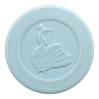 The Fiesta Retired Trivet is a light blue, lead-free china piece with a raised Dancing Lady in a flowing dress and hat, surrounded by concentric ridges near the edge.
