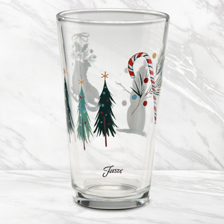 Celebrate the season with the 16 oz. Fiesta Jolly Christmas Cooler Glass – Set of 4 by Moderne Glass. Each clear glass cooler is adorned with festive holiday designs, featuring decorated Christmas trees, a candy cane, ornaments, and pine branches. The word “Fiesta” is printed near the base, highlighting its connection to iconic Fiesta Dinnerware made in the USA. Presented against a white marble background.