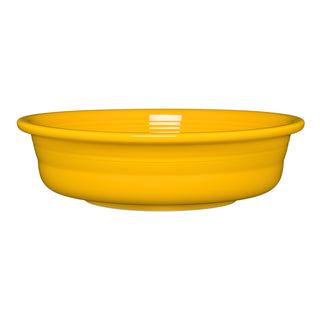 The Fiesta New Retired Classic Rim 10 1/2 Inch Extra Large Serving Bowl (80 OZ) in Daffodil is a shallow, round, bright yellow ceramic bowl with a glossy finish, made in the USA and shown on a white background.