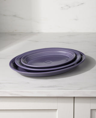 A Fiesta Lavender 9 5/8 inch small oval serving platter sits on a white marble countertop with a white cabinet below and a light-colored marble backsplash in the background.