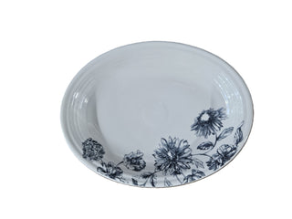The Fiesta Botanical Floral Black 11 5/8 Inch Medium Oval Serving Platter features a white ceramic design with a detailed black botanical floral pattern along the rim, showcasing elegant flowers and leaves. Displayed against a plain white background.