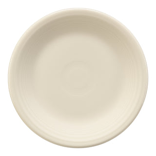 The Fiesta Classic Rim 7 1/4 Inch Salad Plate in Linen is a cream-colored ceramic plate with a slightly raised rim and delicate circular patterns, showcasing American craftsmanship in lead-safe china.