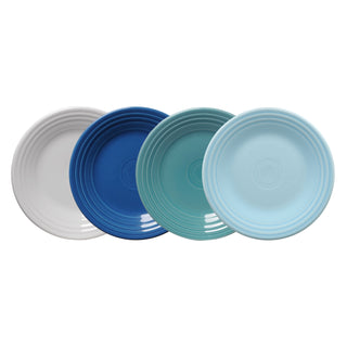 The Fiesta Mixed Coastal Blues Classic Rim 9 Inch Luncheon Plate Set includes four plates in white, dark blue, teal, and light blue, each with a simple ridged rim design. Proudly made in the USA.
