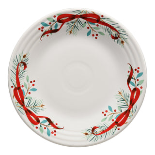 The Fiesta Holly Berry Christmas Garland Classic Rim 9 Inch Luncheon Plate features red ribbons, green pine branches, and red berries around the rim, making it perfect festive dinnerware for the holidays.