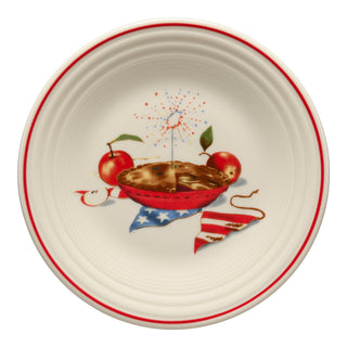 The Fiesta Americana Apple Pie Classic Rim 9 Inch Luncheon Plate features a white base, red rim, and an illustration of pie, apples, flag napkin, and fireworks—ideal patriotic dinnerware for any Americana-themed table setting.
