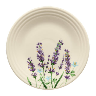 The Fiesta Lavender Bloom Classic Rim 9 Inch Luncheon Plate features a cream base with hand-painted purple lavender flowers, green stems, and blue and yellow accents. This lead-safe china adds elegance to any table setting.