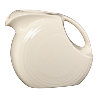 The Fiesta 67 OZ Large Disk Pitcher in Linen features a vintage-inspired round body, smooth glossy finish, angular spout, and large curved handle. Lead-safe and shown on a white background.