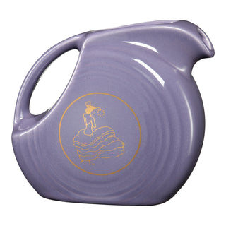 The Fiesta 2026 Lavender Anniversary Small Disk Pitcher by Fiesta features a circular body, curved handle, and a gold outline of a woman in a ruffled dress with a fan. Made in the USA from lead-safe china.