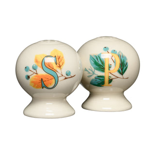 The Fiesta Autumn Fields 2 5/8 Inch Salt and Pepper Shaker Set features two round ceramic shakers with autumn-inspired designs—one adorned with an “S” and yellow leaves, and the other with a “P” and green pine needles—both set against a cream background for botanical floral charm.