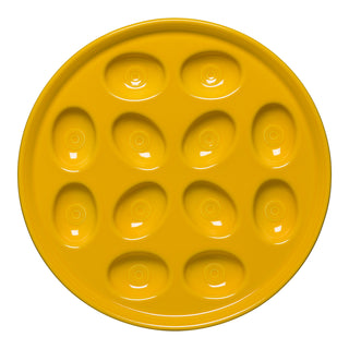 The Fiesta New Retired Round Egg Serving Platter in Daffodil is 11 1/4 inches, featuring twelve oval indentations for deviled eggs arranged in a circular pattern. This bright yellow plate is dishwasher safe.