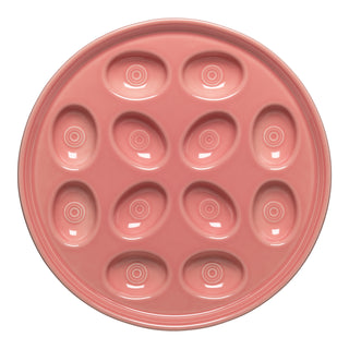 The Fiesta New Retired Round Egg Serving Platter in Peony is an 11 1/4-inch pink ceramic plate with twelve oval indentations for deviled eggs. Dishwasher safe and made in the USA.