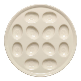 The Fiesta Round Egg Serving Platter in Linen features twelve oval indents arranged in a circle on an 11 1/4-inch cream-colored ceramic tray, perfect for serving deviled eggs or appetizers.