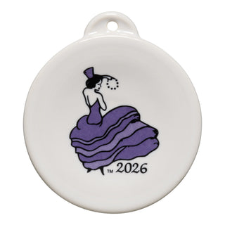 The Lavender 2026 Dancing Lady Ornament by Fiesta is a round white ceramic keepsake featuring a lady in a lavender gown and hat holding a necklace, with "2026" below her.