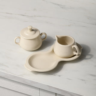 A New Retired Linen 4-Piece Sugar Bowl and Creamer Set with Tray by Fiesta is displayed on a white marble countertop.
