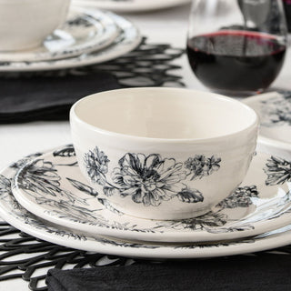 A close-up highlights the Fiesta Factory Direct Botanical Floral Black Classic Bistro 3-piece Place Setting for 1, featuring a white ceramic bowl and rim dinner plate with floral designs, paired with black napkins and red wine on a crisp white tablecloth.