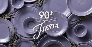 A flat-lay arrangement of lavender-colored ceramic plates and bowls with a central white script overlay reading '90th Anniversary FIESTA 1936-2026,' surrounded by dried lavender sprigs.