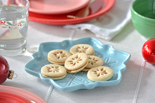Cookies on a blue snowflake shaped plate with festive decorations in the background