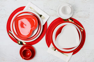 Scarlet and White heart plates with gold silverware on regular plates and a white table